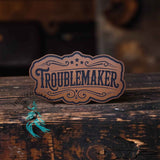 Leather hat patch reading All-American Troublemaker in patriotic styling
