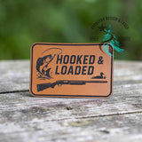 Leather hat patch reading Hooked and Loaded with hunting and fishing styling