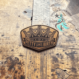 Copper toned leather hat patch reading Petty Since Birth