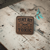 Close-up of the engraved Tiny Bit Toxic leather hat patch