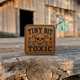Tiny Bit Toxic leather hat patch shown at an angle